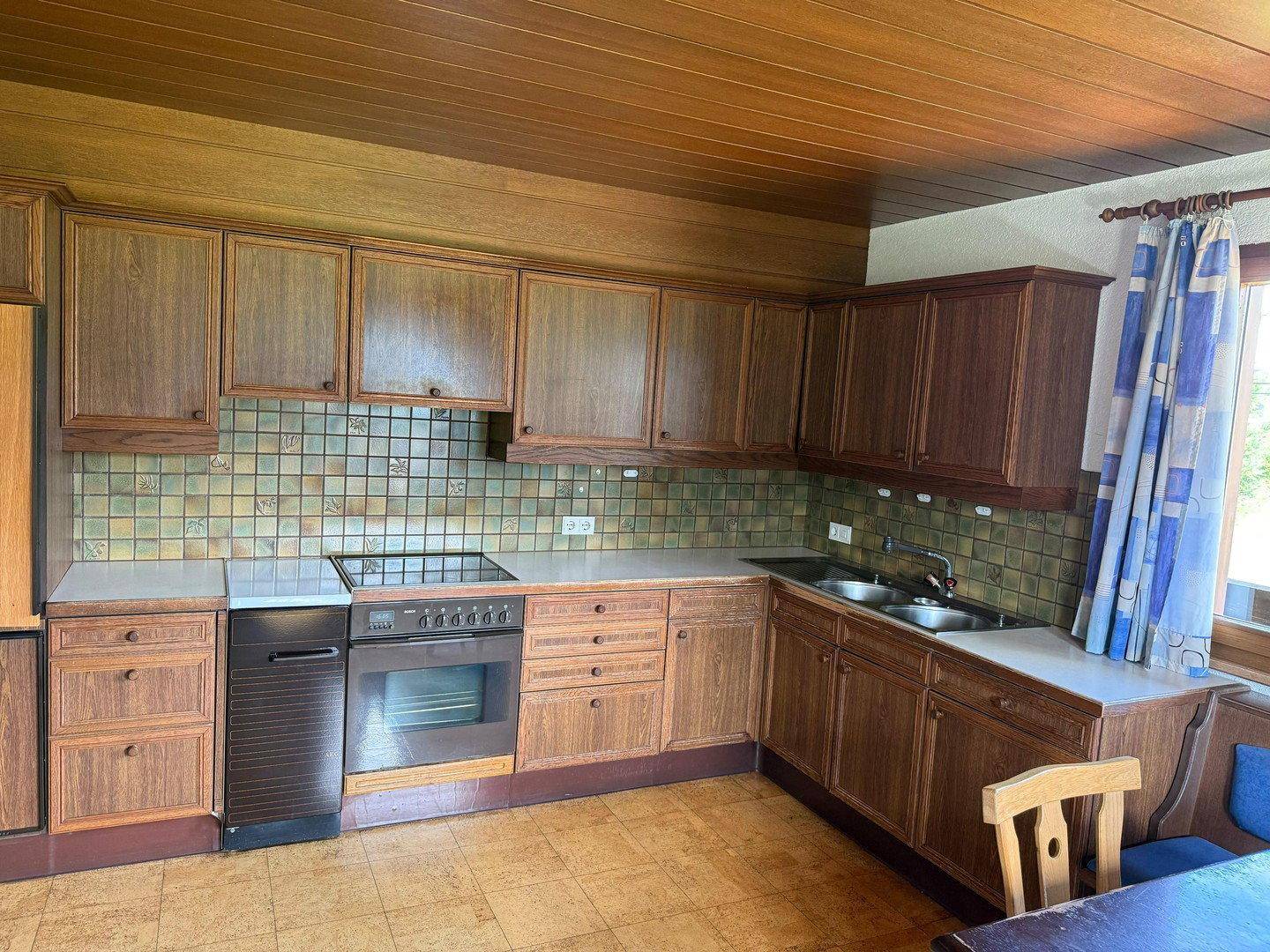 Traditionelle Küche mit Holzschränken, gefliestem Spritzschutz und integrierten Geräten.