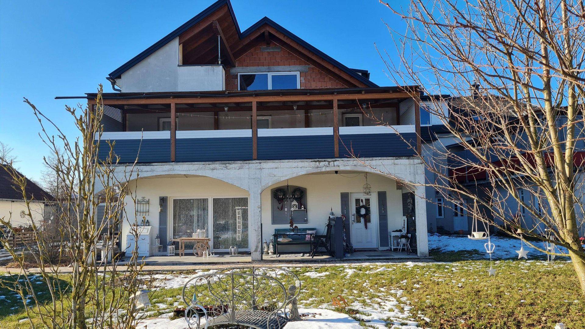 Rückansicht des Hauses mit überdachter Terrasse und einem weitläufigen Gartenbereich im Winter.
