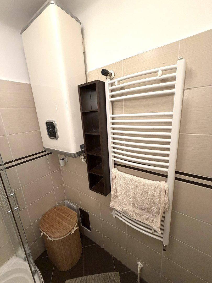 Badezimmer mit Warmwasserboiler und beheiztem Handtuchhalter, praktische Ausstattung.
