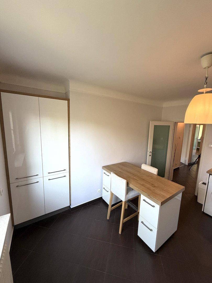 Heller Küchenbereich mit weißem Hochschrank und einem funktionalen Esstisch mit Stühlen.
