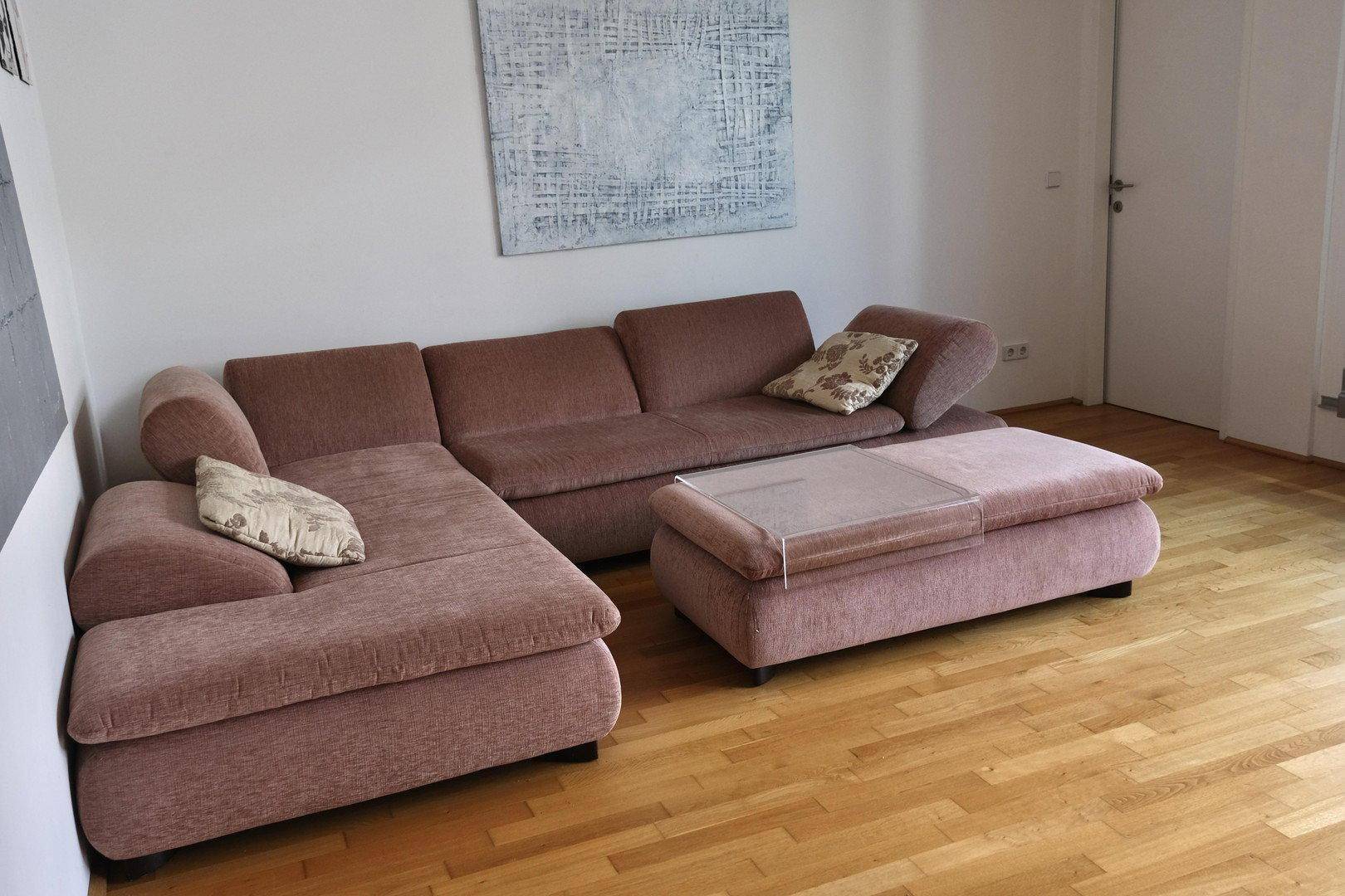 Gemütliches Wohnzimmer mit beigem Ecksofa, Couchtisch und hellem Parkettboden.