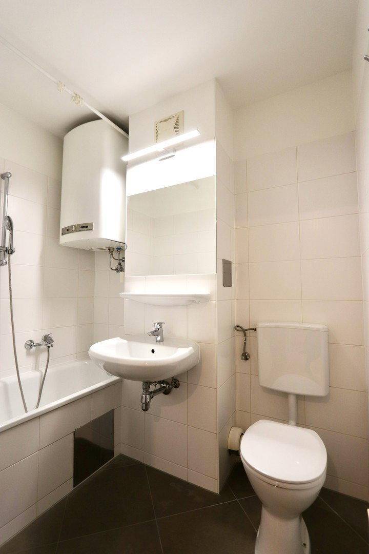 Funktionales Badezimmer mit Badewanne, WC, Waschbecken und Wandspiegel, in gutem Zustand.