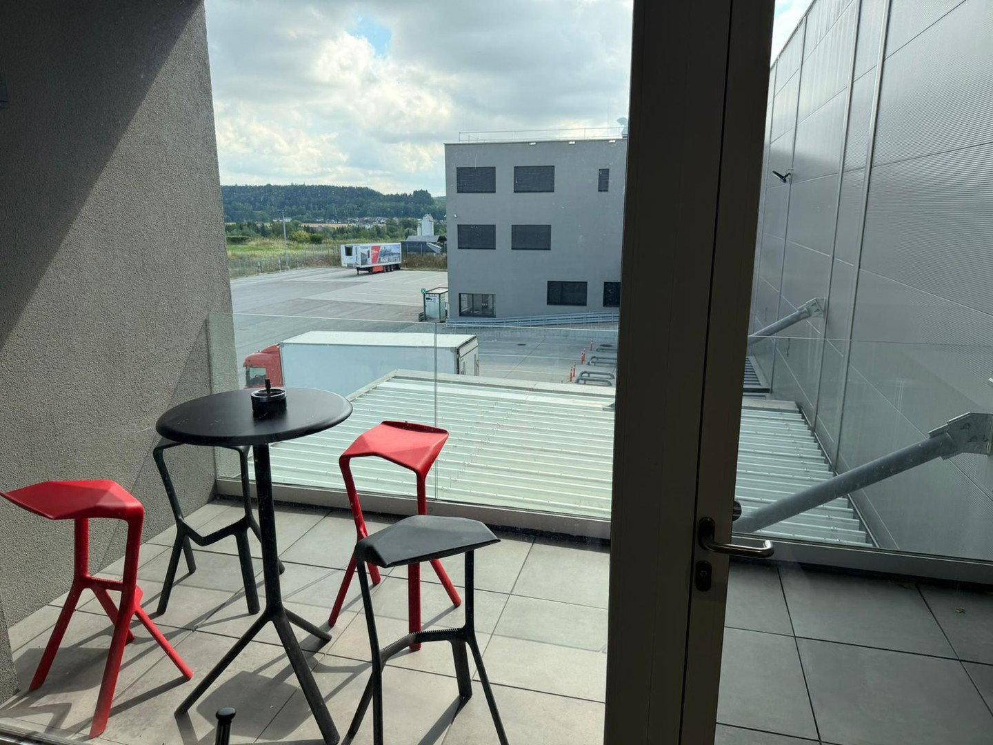 Kleiner Balkon mit Tisch und Stühlen, bietet einen Blick auf das umliegende Gelände.