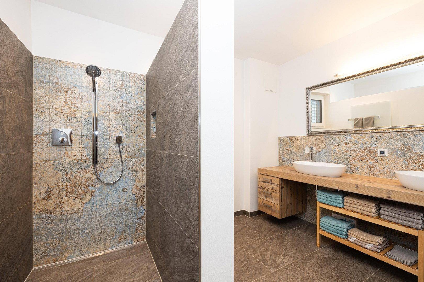 Elegantes Badezimmer mit großer begehbarer Dusche und dekorativen Fliesen an der Wand.