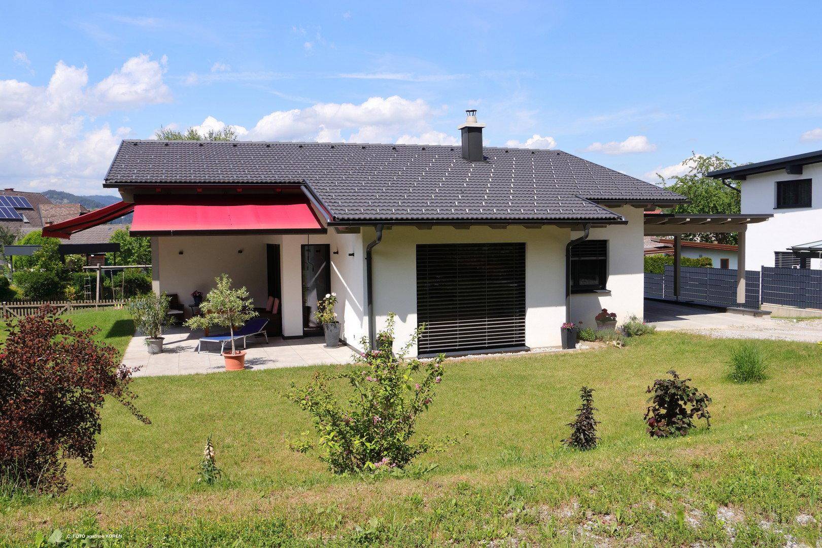 Freistehendes Einfamilienhaus mit Terrasse, Markise und großem Garten in ländlicher Umgebung.