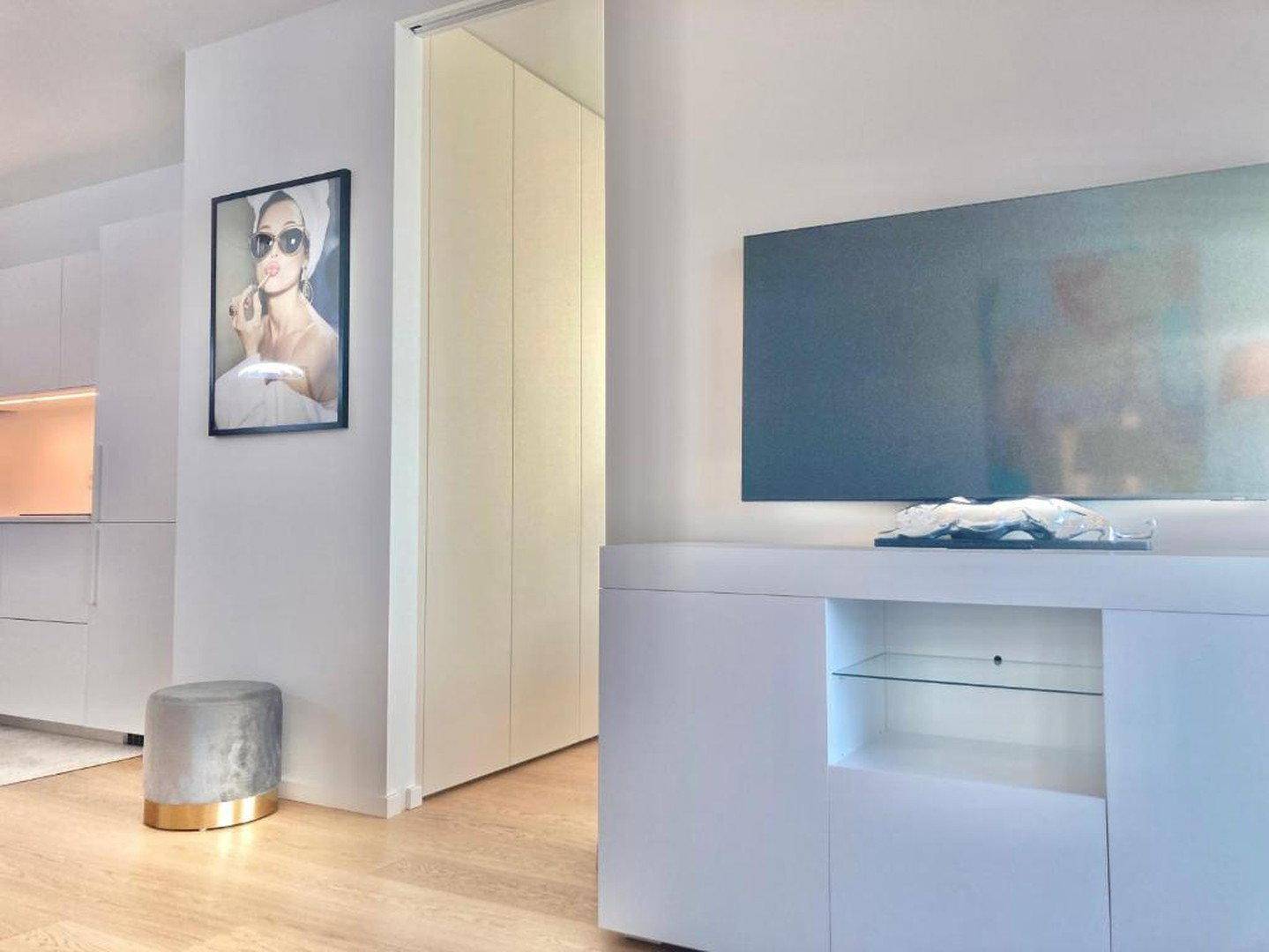 Moderner Wohnbereich mit weißem TV-Möbel, stilvoller Dekoration und integrierten Schränken.