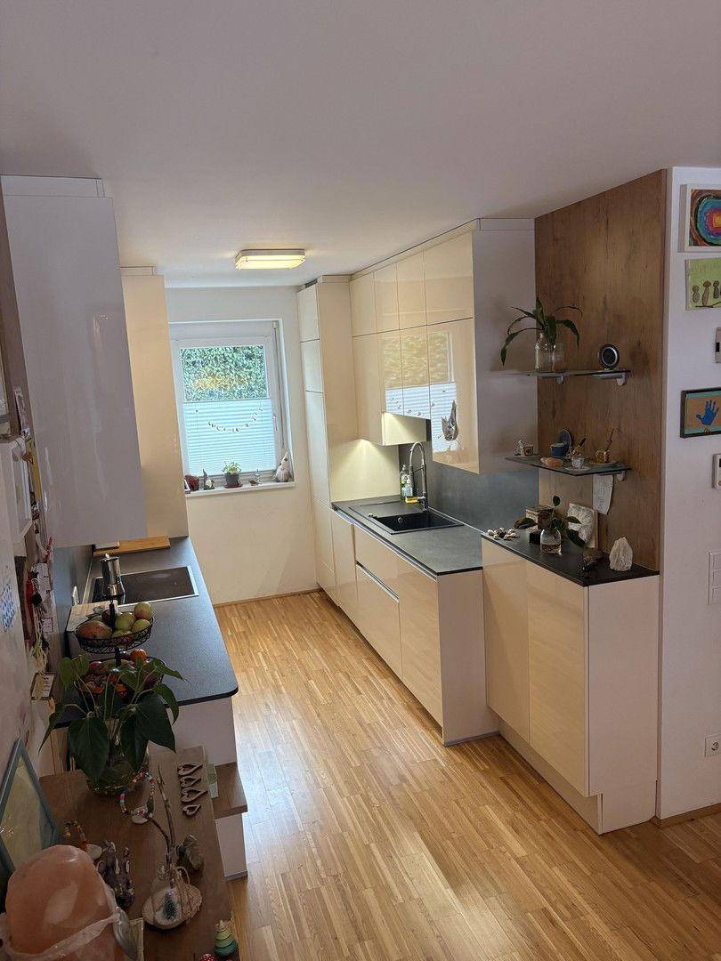 Helle, moderne Küche mit integrierten Geräten, viel Stauraum und einem Fenster mit Blick ins Grüne.