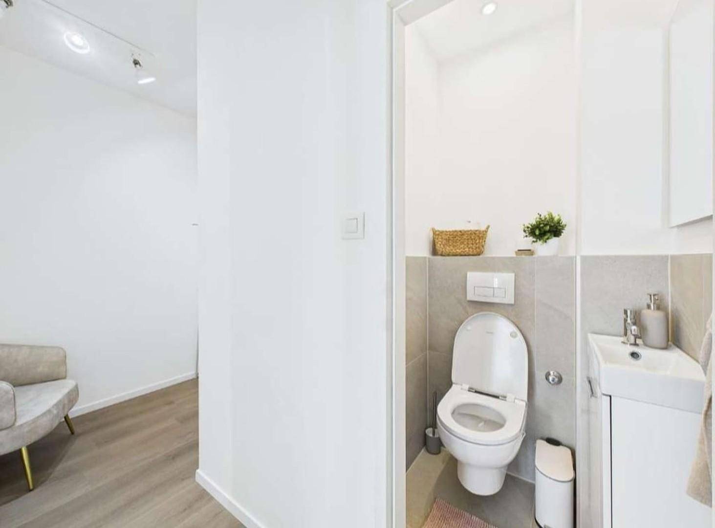 Kleines Gäste-WC mit wandhängender Toilette, Waschbecken und modernen Fliesen.