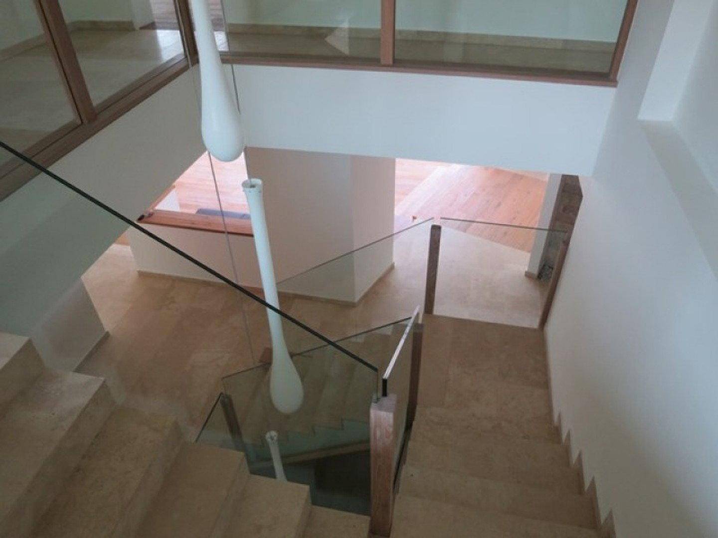 Blick von oben auf die moderne Treppe mit Glasgeländer und hellen Stufen.