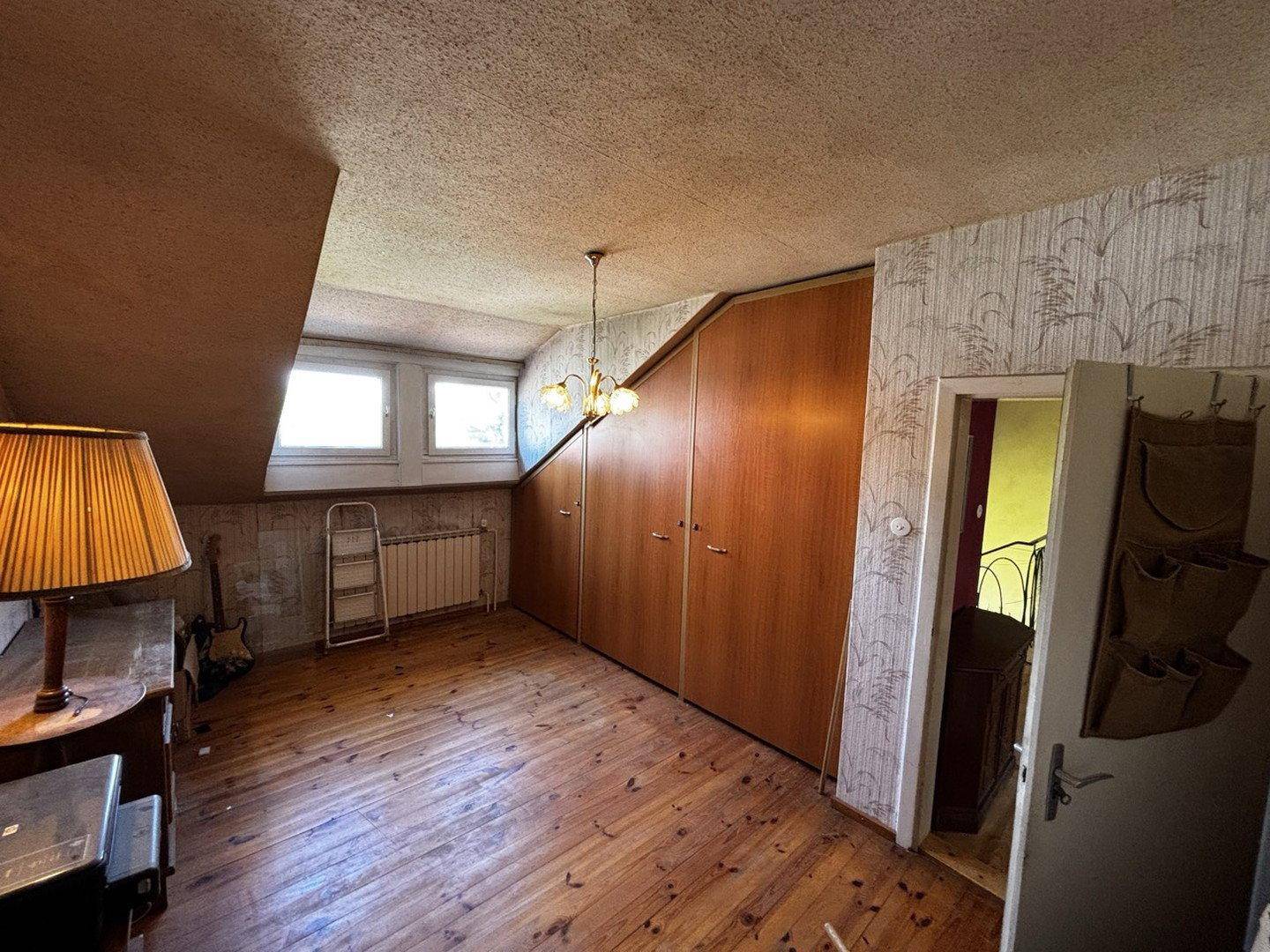 Schlafzimmer im Dachgeschoss mit Holzboden, Einbauschränken und Dachschrägen.