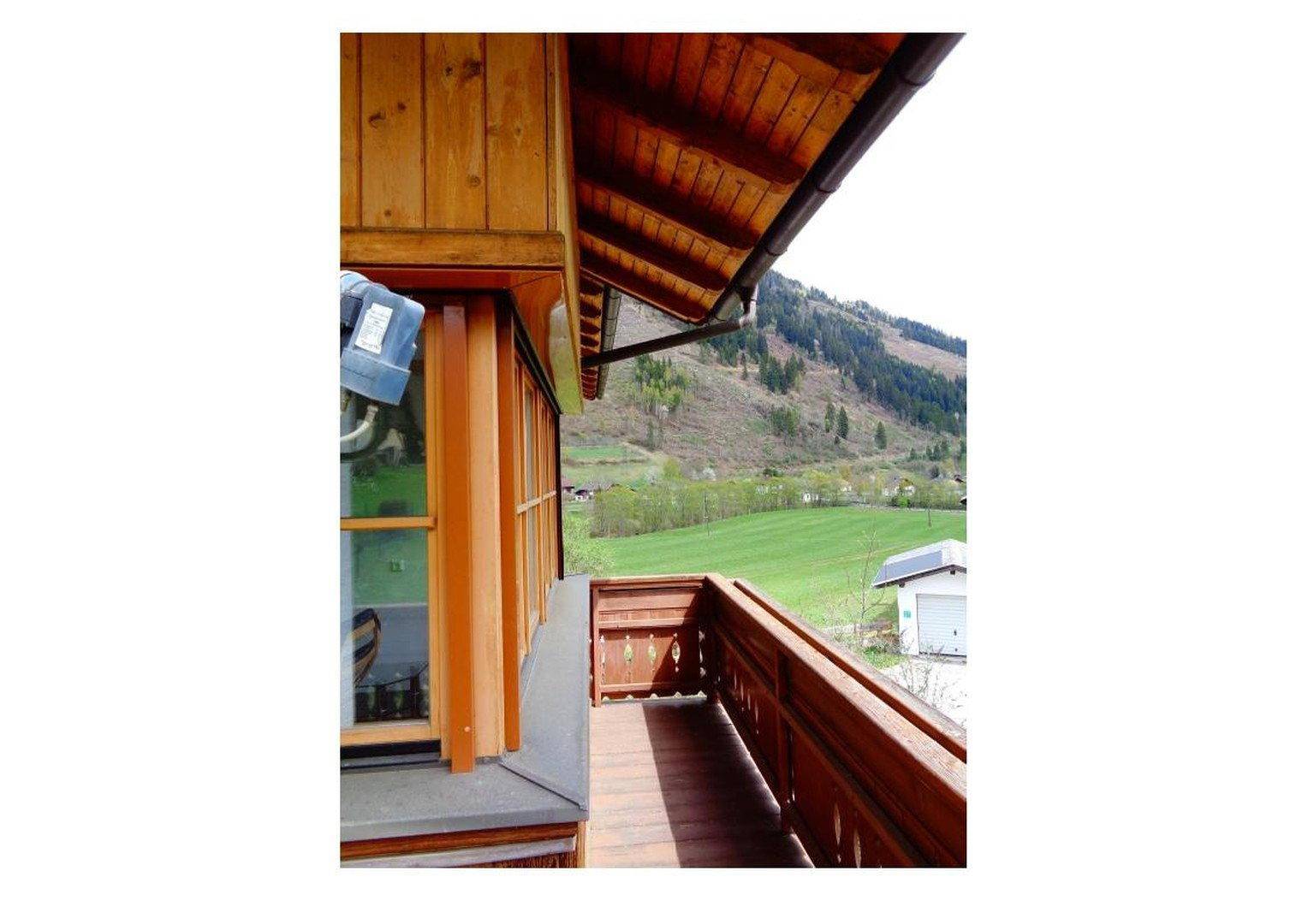 Balkon mit Holzboden und Geländer, bietet einen weiten Blick auf die umliegenden Berge und Natur.