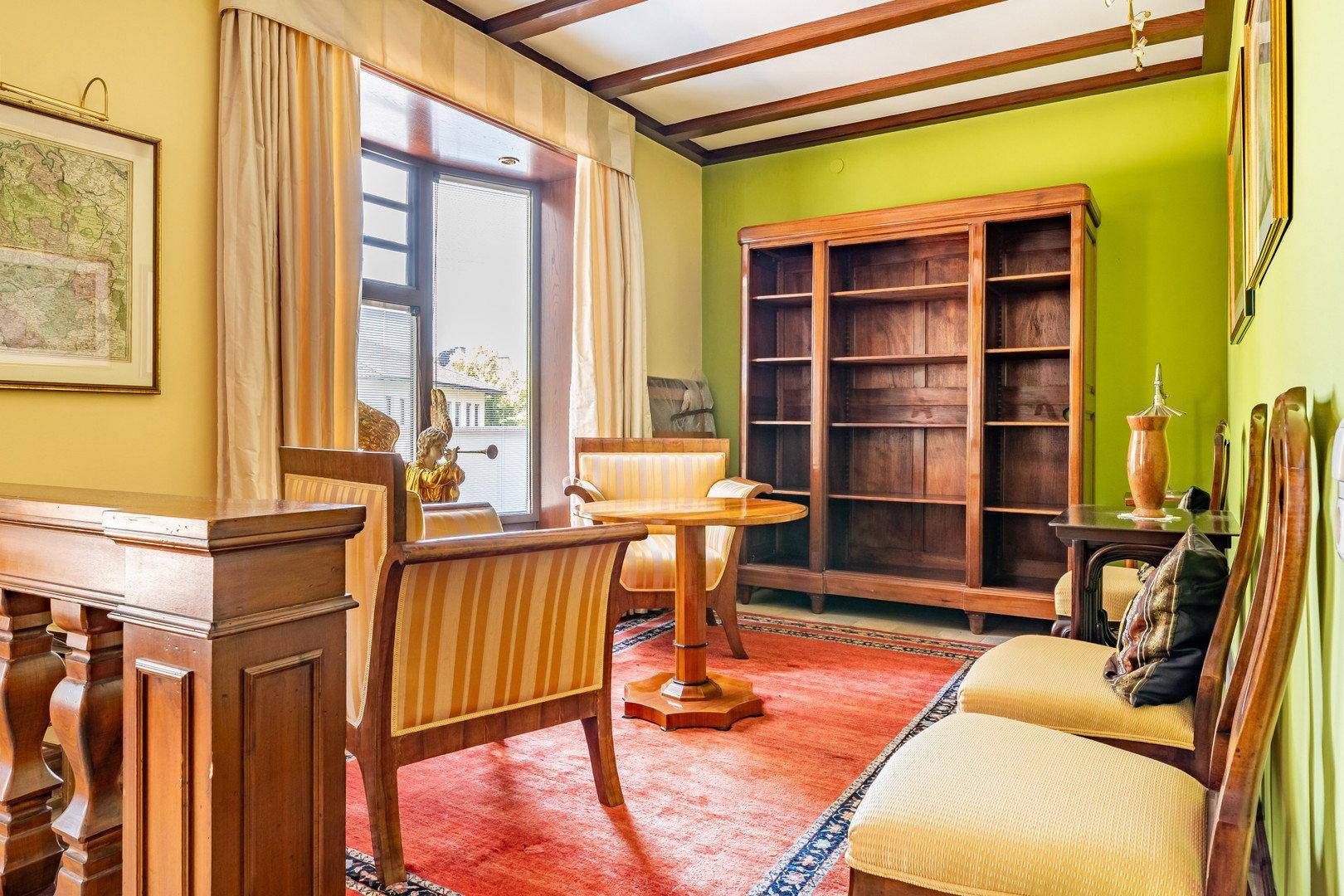Wohnbereich mit Holzbalkendecke, grünen Wänden und klassischer Einrichtung.