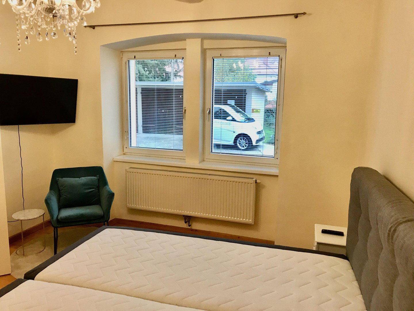 Schlafzimmer mit Bett und Fenster, das einen Blick auf die Straße bietet.
