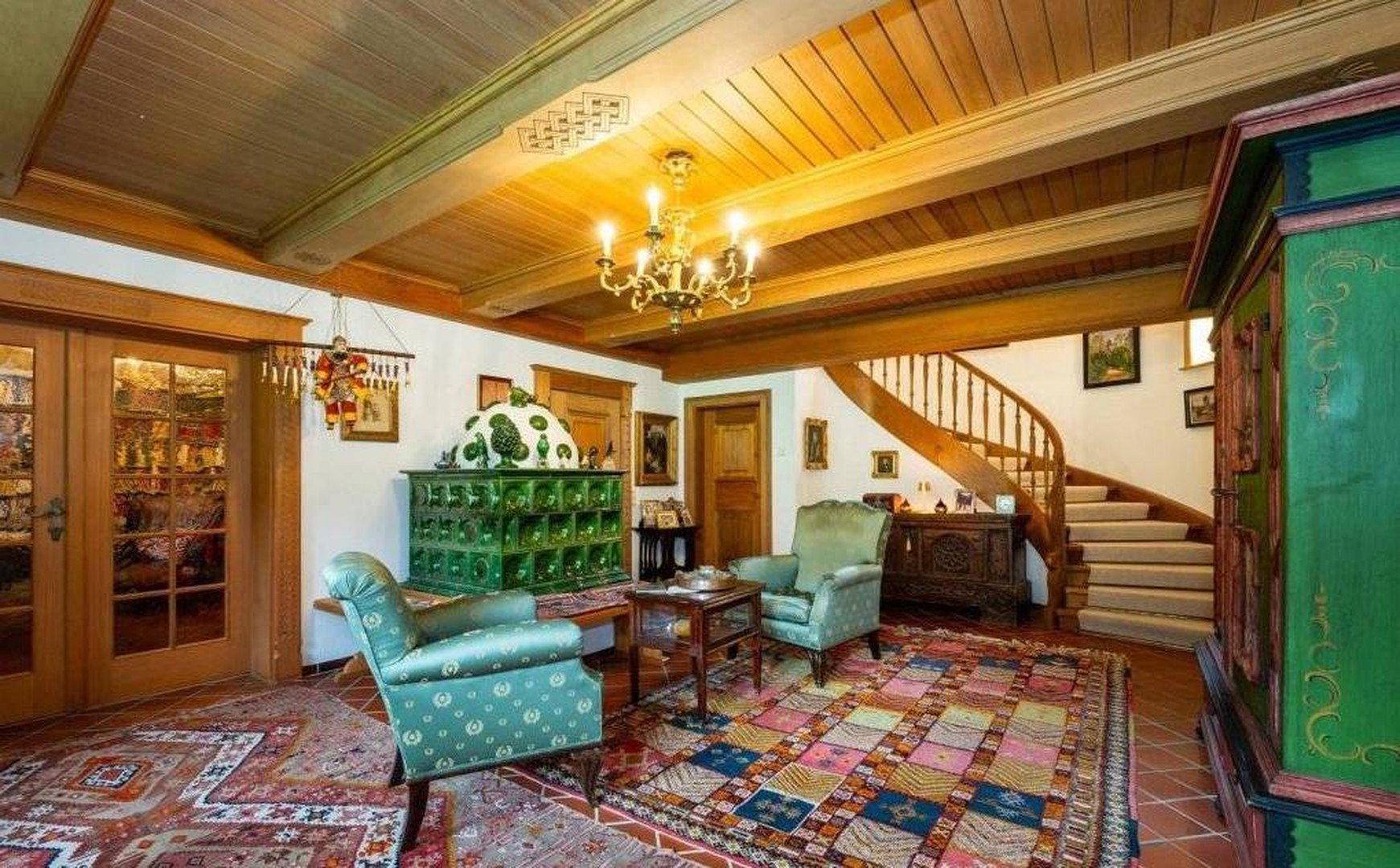 Gemütliches Wohnzimmer mit Kachelofen, Holzbalkendecke und traditionellen Möbeln.