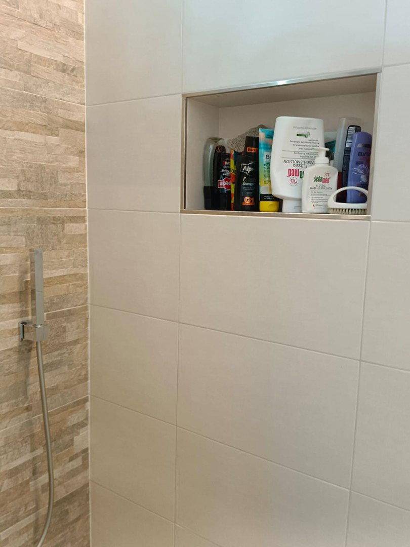 Praktische Nische in der Duschwand für Badartikel in einem modern gefliesten Badezimmer.