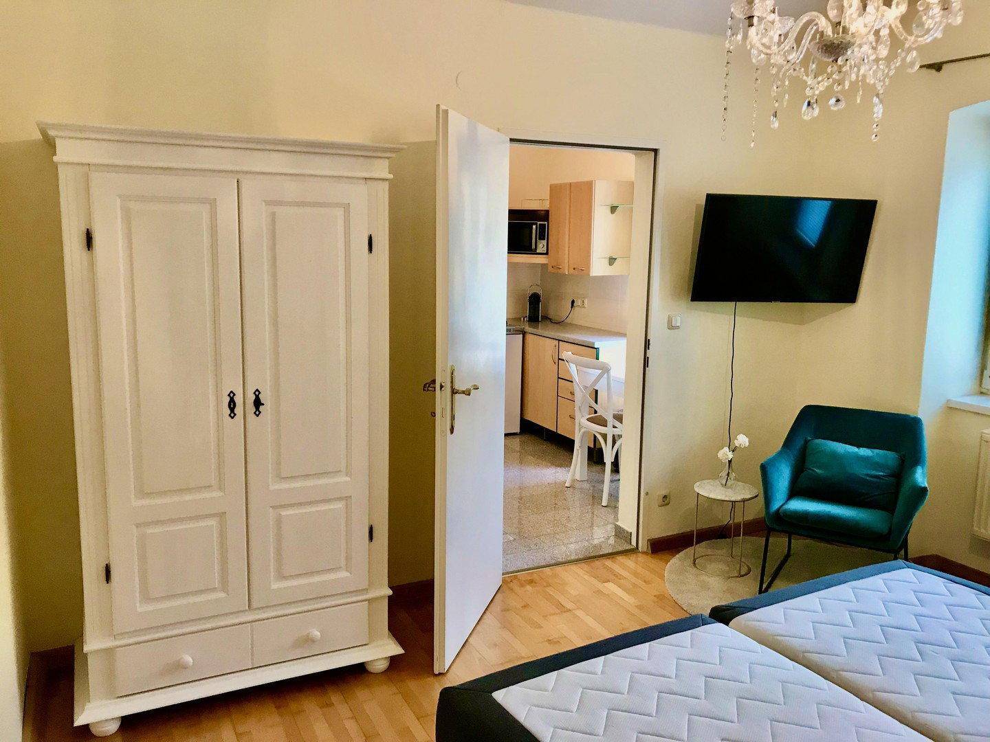 Gemütliches Schlafzimmer mit weißem Kleiderschrank und Zugang zu einer kleinen Küchenzeile.