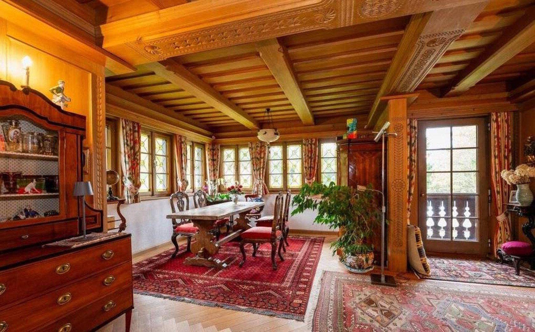 Heller Essbereich mit Holzbalkendecke, großem Esstisch und Zugang zum Außenbereich.