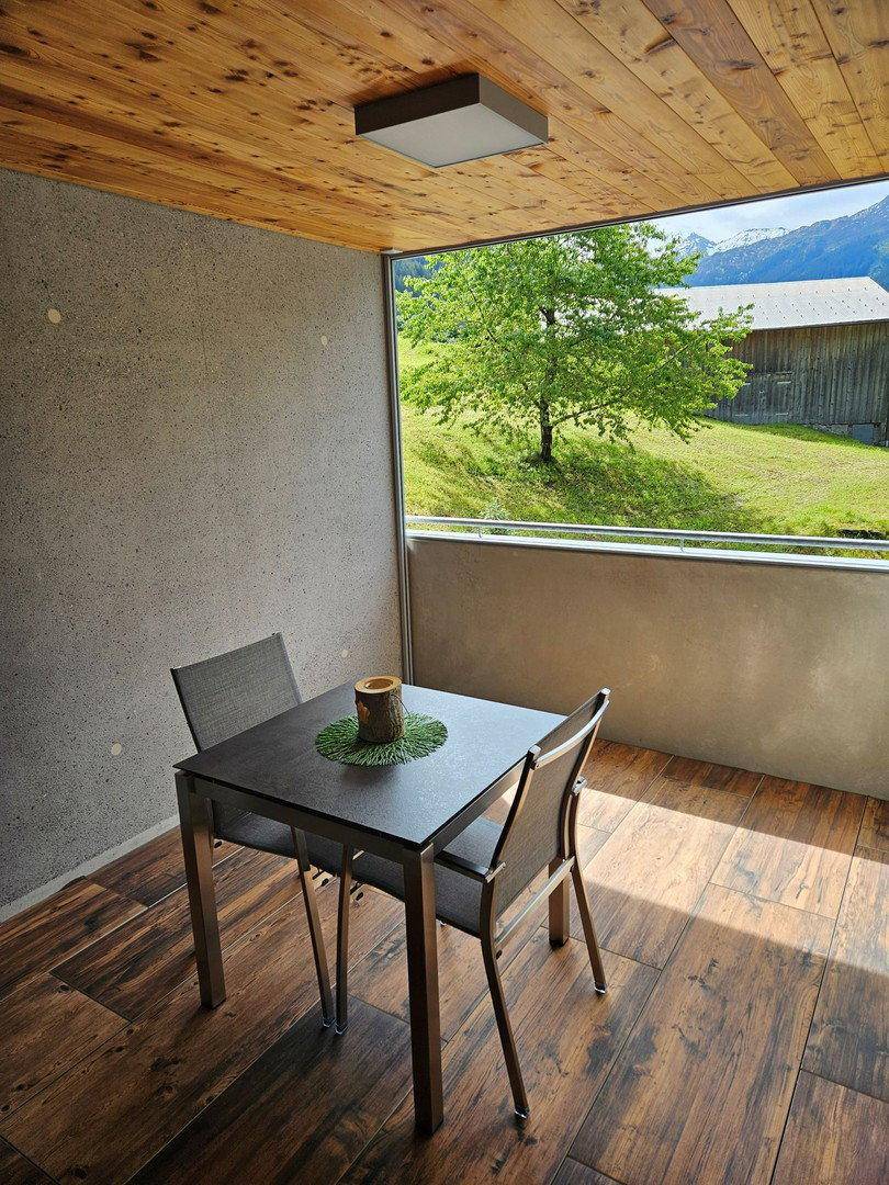 Gemütlicher Balkon mit Holzboden, Sitzgelegenheiten und weitem Blick auf die umliegende Natur.