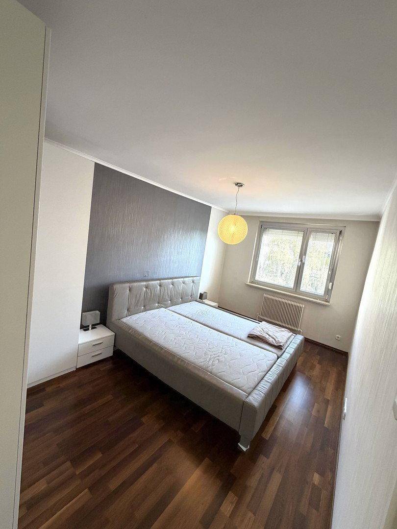 Gemütliches Schlafzimmer mit Doppelbett, Nachttischen und dunklem Holzboden.