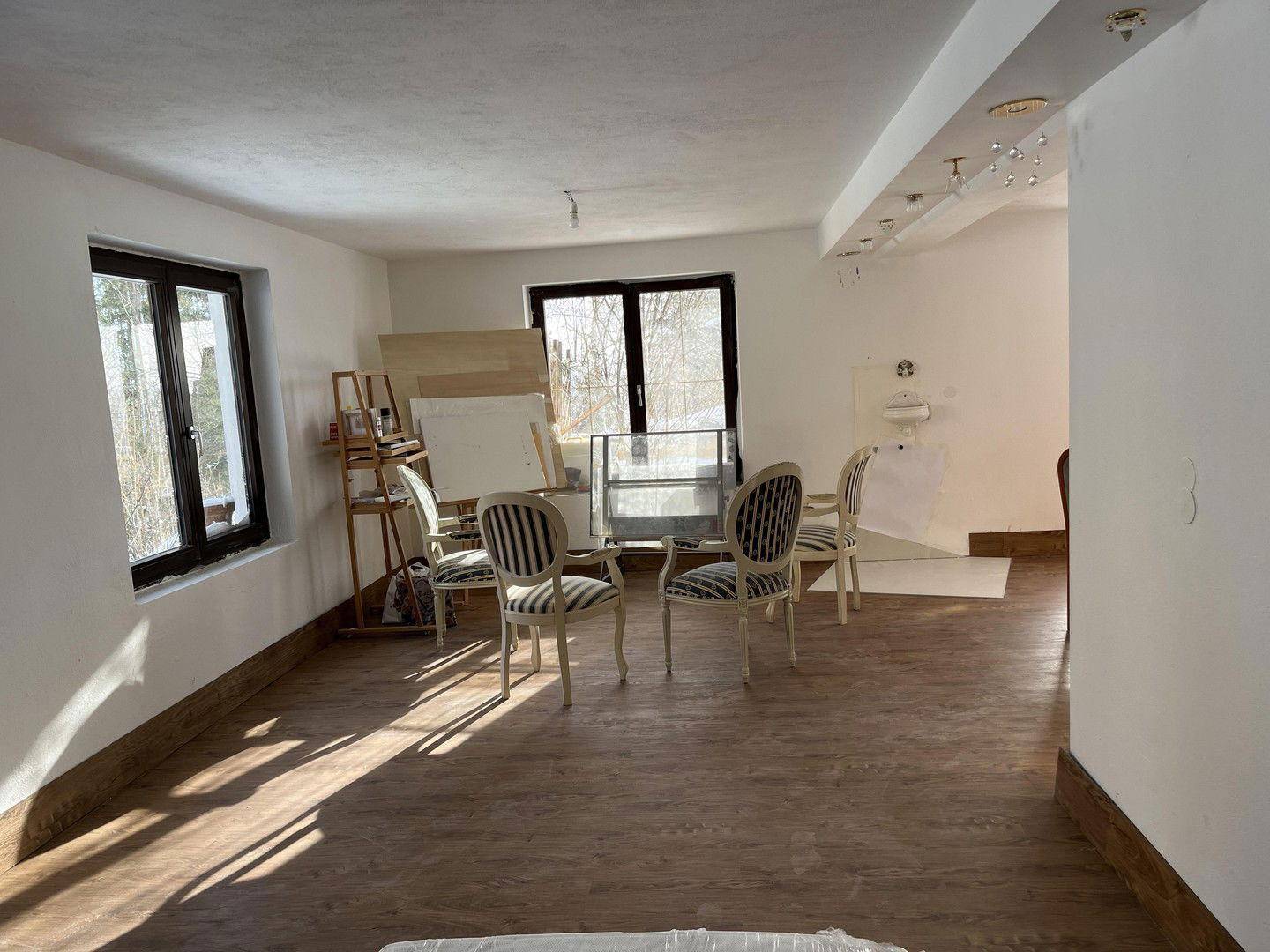 Heller Wohnbereich mit Holzboden, großen Fenstern und viel Platz für individuelle Gestaltung.