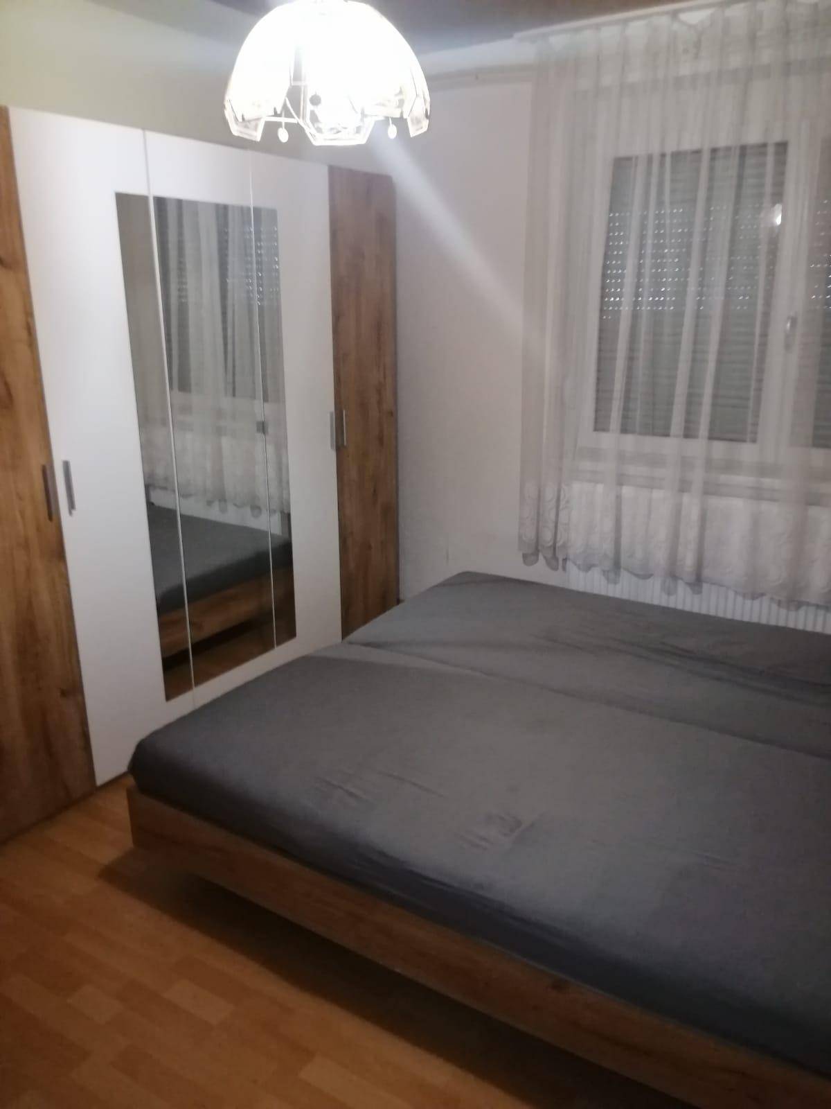 Schlafzimmer mit Holzbett, Spiegelschrank und Parkettboden.