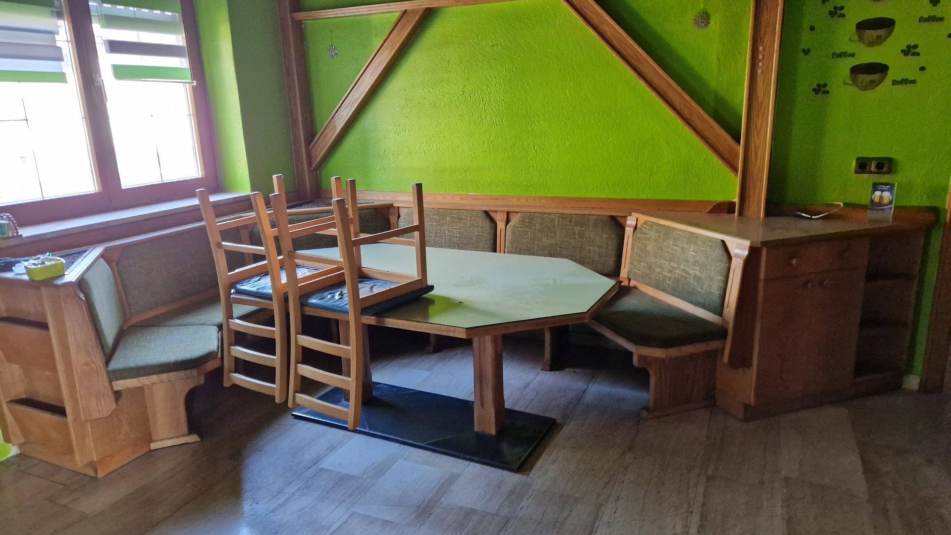 Essbereich mit Holzbänken, passendem Tisch und grünen Wänden.
