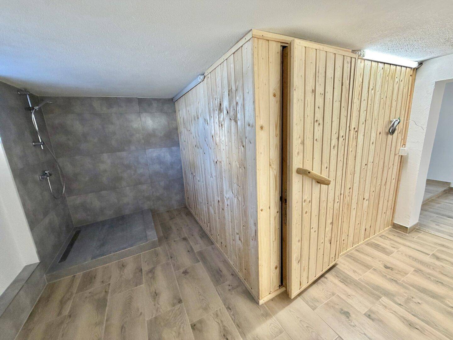 Moderner Wellnessbereich mit Sauna und begehbarer Dusche im Untergeschoss.