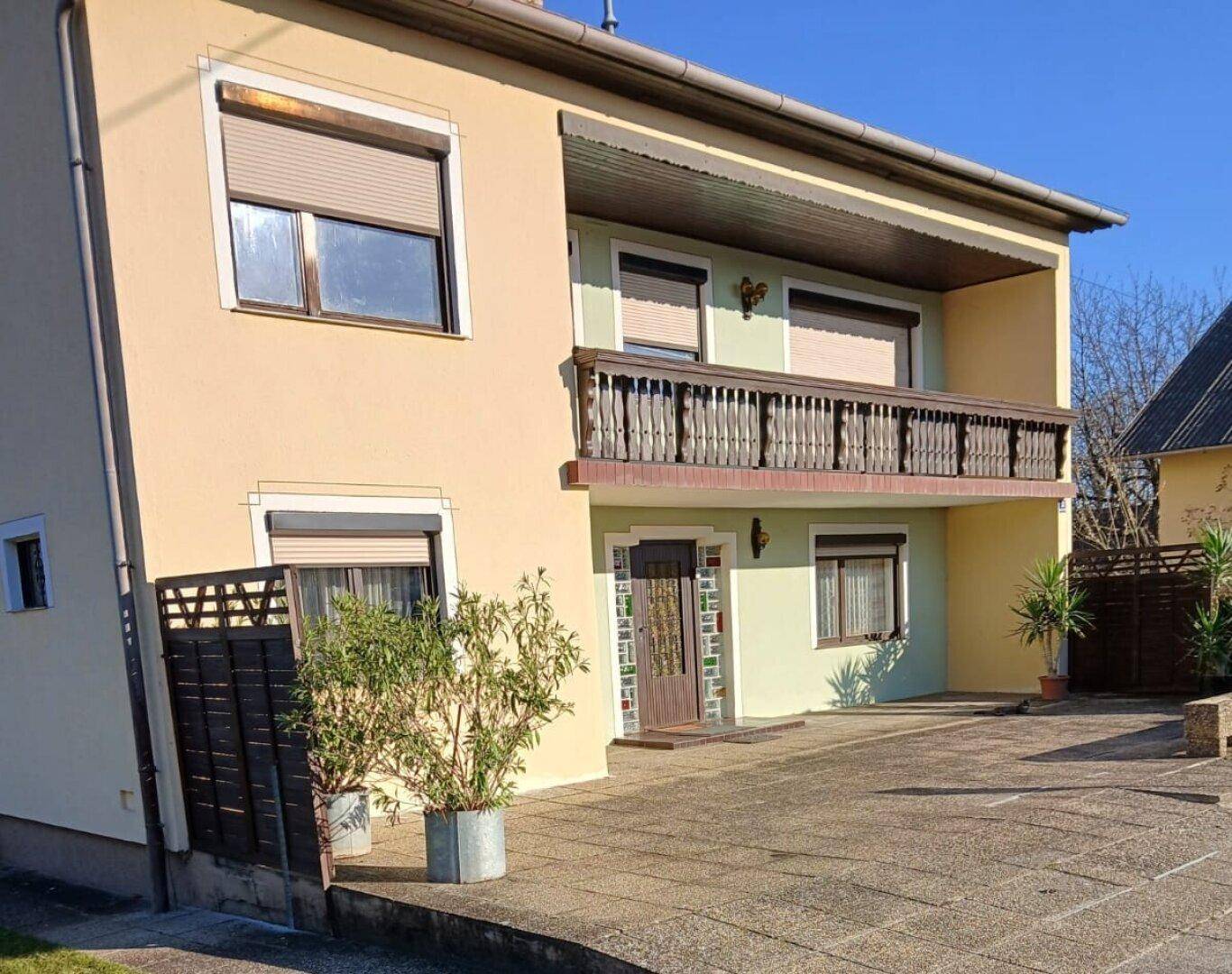 Vorderansicht des Hauses mit Eingangsbereich, Balkon und gepflegter Auffahrt.