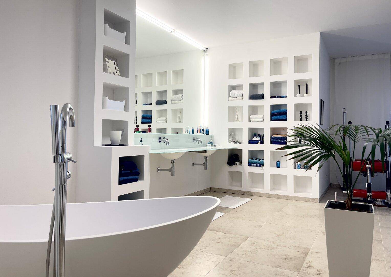 Luxuriöses Badezimmer mit freistehender Badewanne, Doppelwaschbecken und integrierten Regalen.