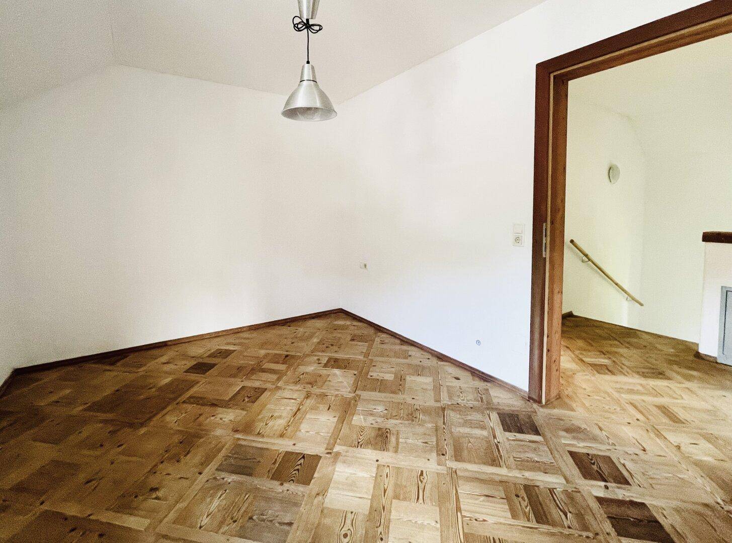 Heller Flur mit Holzboden und Zugang zu weiteren Räumen sowie einer Treppe.