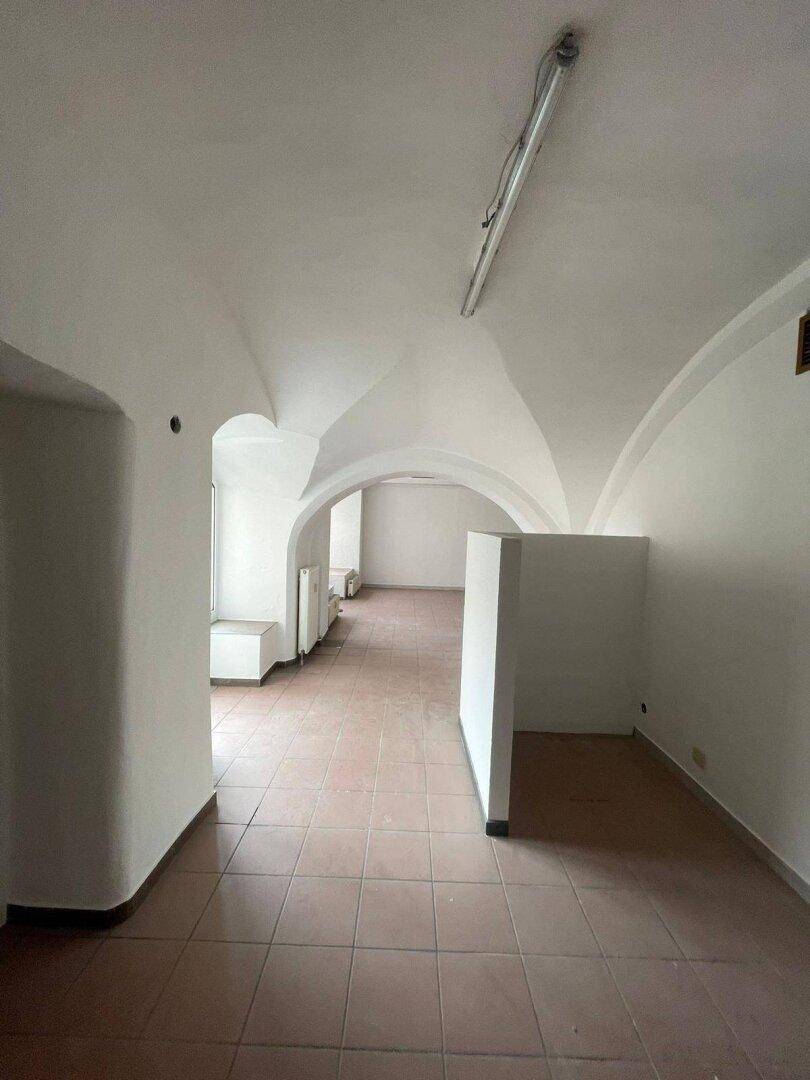 Langer Gewerberaum mit hellbraunen Fliesen, weißen Wänden und mehreren eleganten Gewölbebögen.