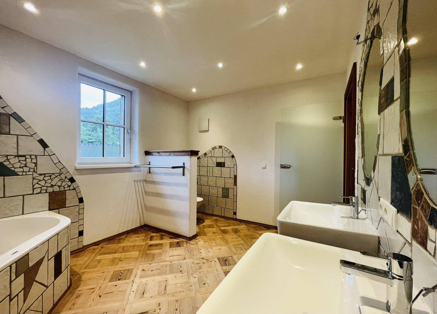 Geräumiges Badezimmer mit Doppelwaschbecken, Badewanne und kreativen Mosaikfliesen.