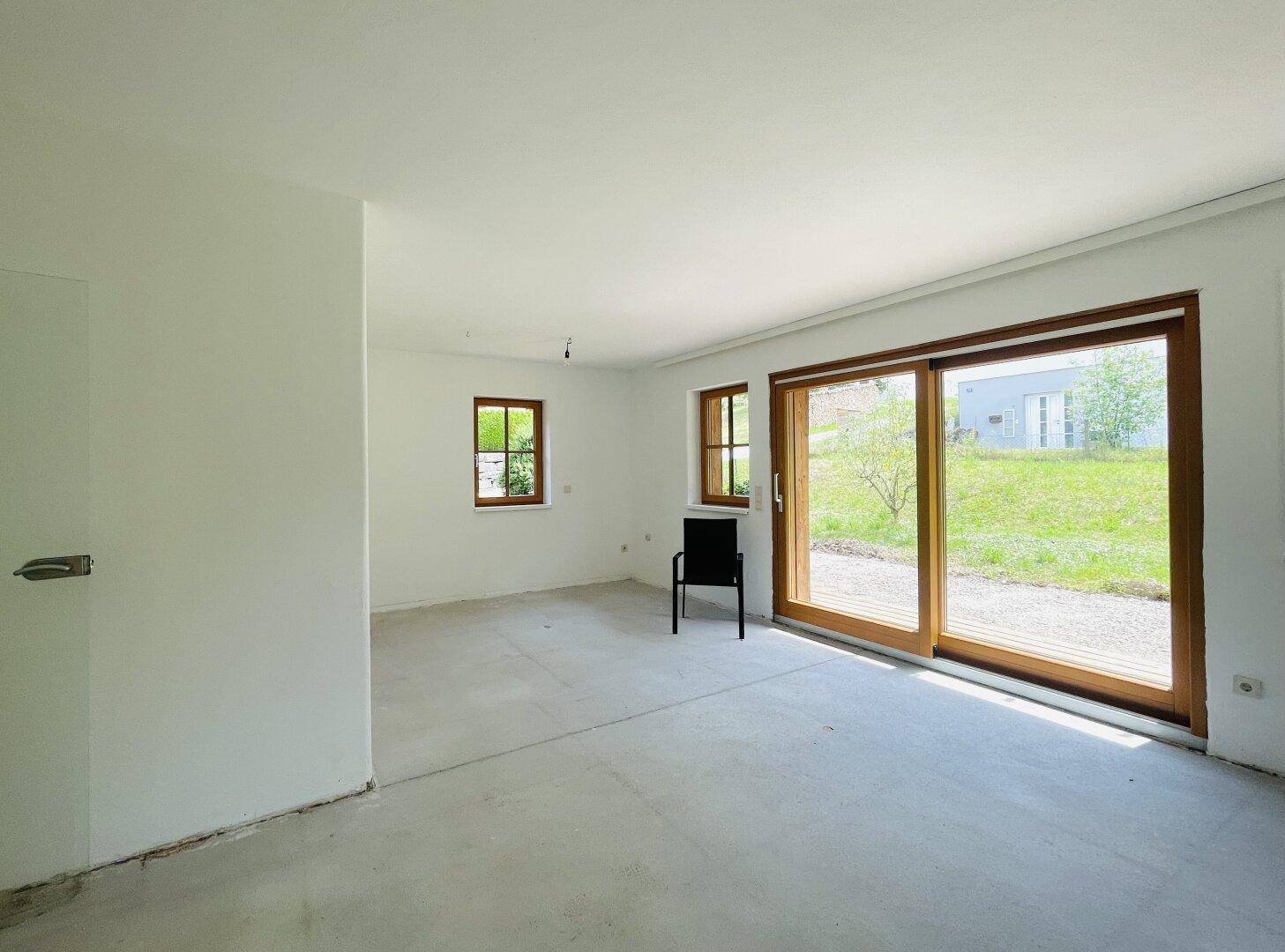 Heller Raum mit großen Schiebetüren zum Garten und Blick ins Grüne.