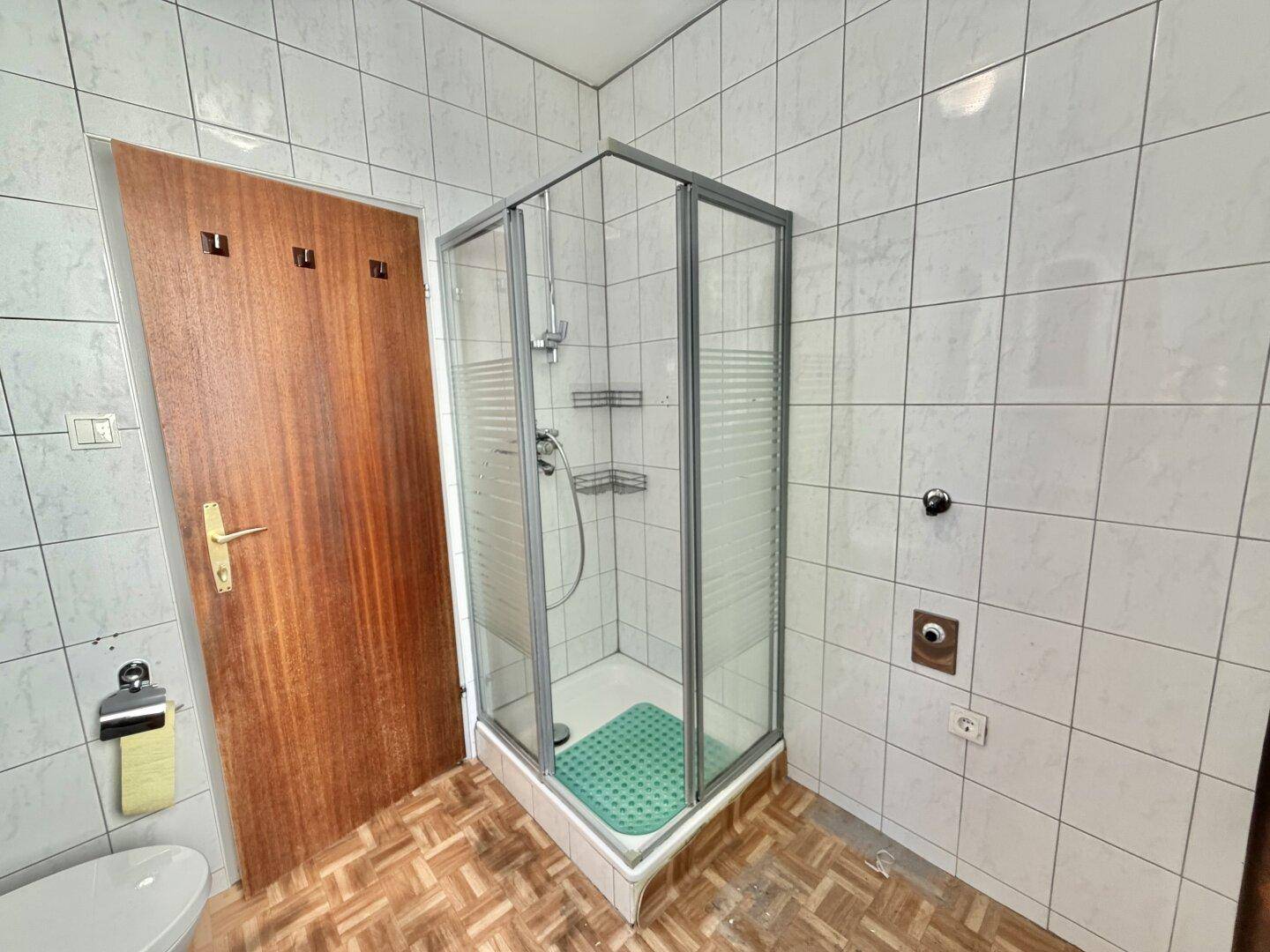 Badezimmer mit weiß gefliesten Wänden und einer Eckduschkabine.
