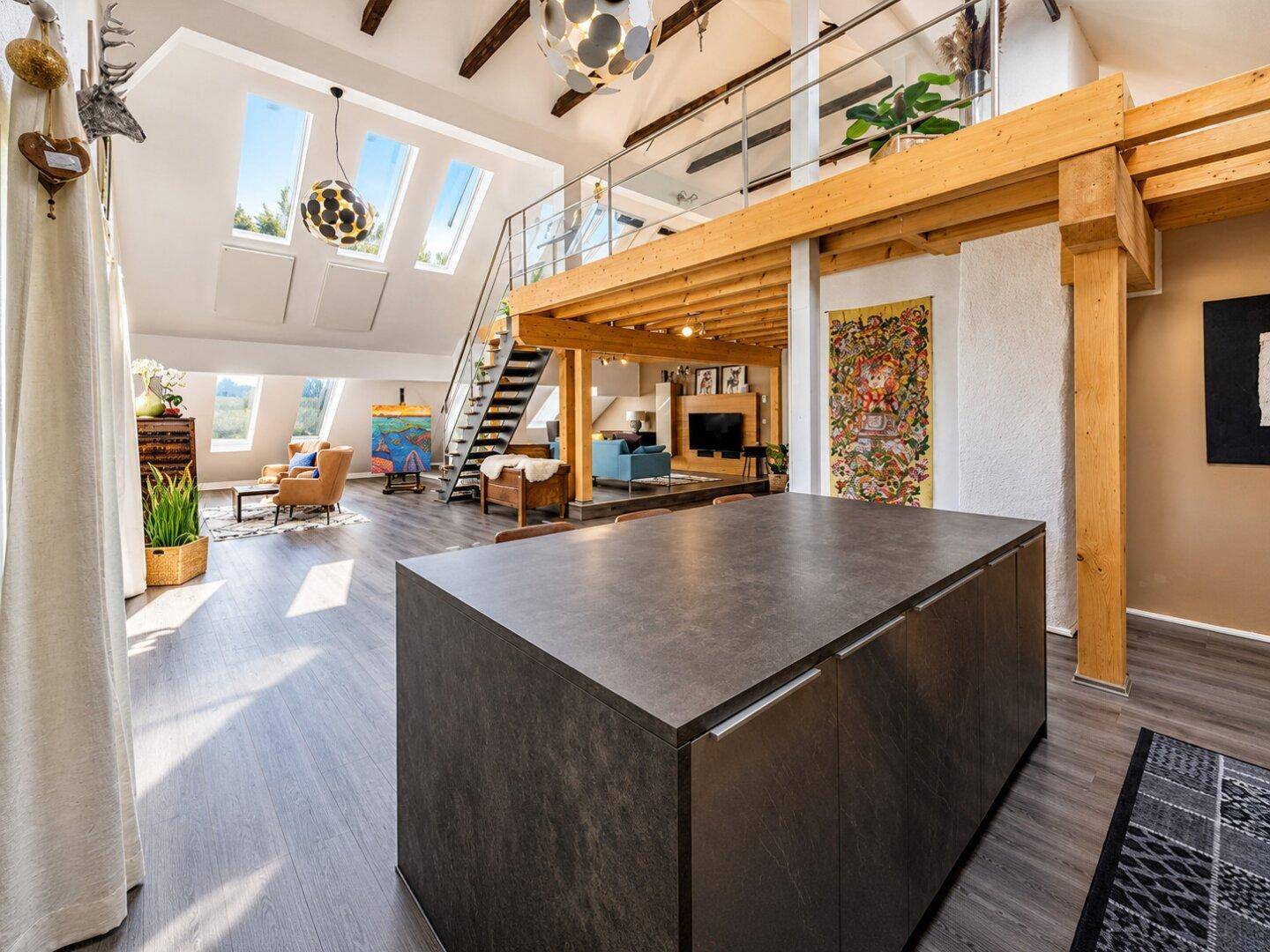 Geräumiges Loft mit offener Küche, Galerie und hohen Decken, durchflutet von natürlichem Licht.