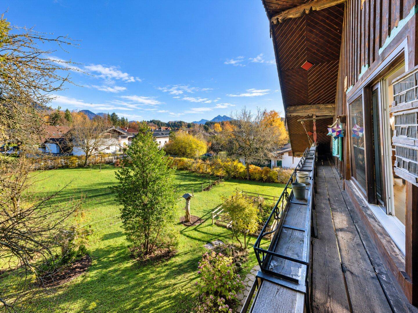 Langer Holzbalkon mit Blick auf die Berge und die umliegende grüne Landschaft.
