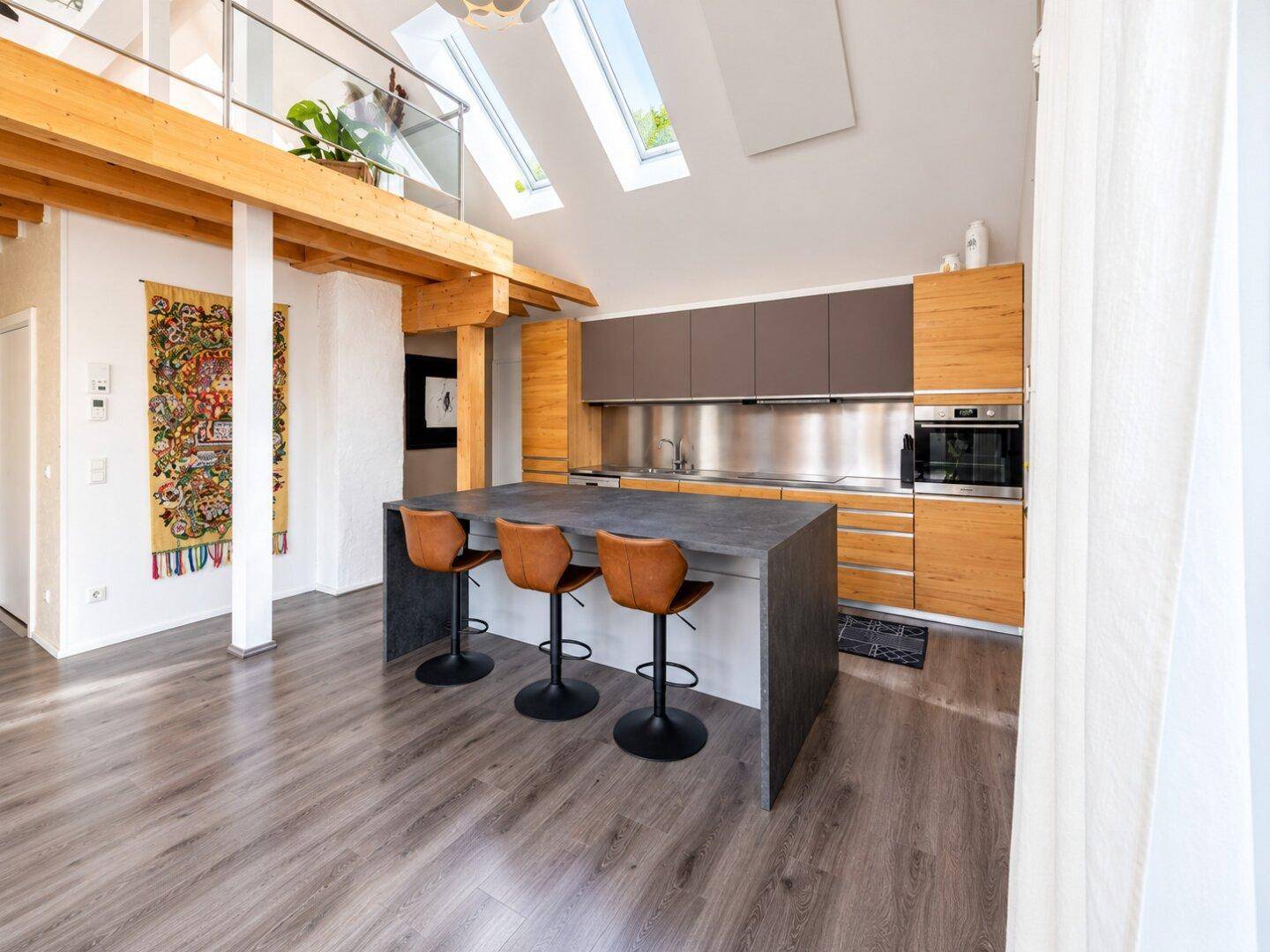 Moderne Einbauküche mit Kücheninsel, Barhockern und Edelstahl-Rückwand im offenen Wohnbereich.