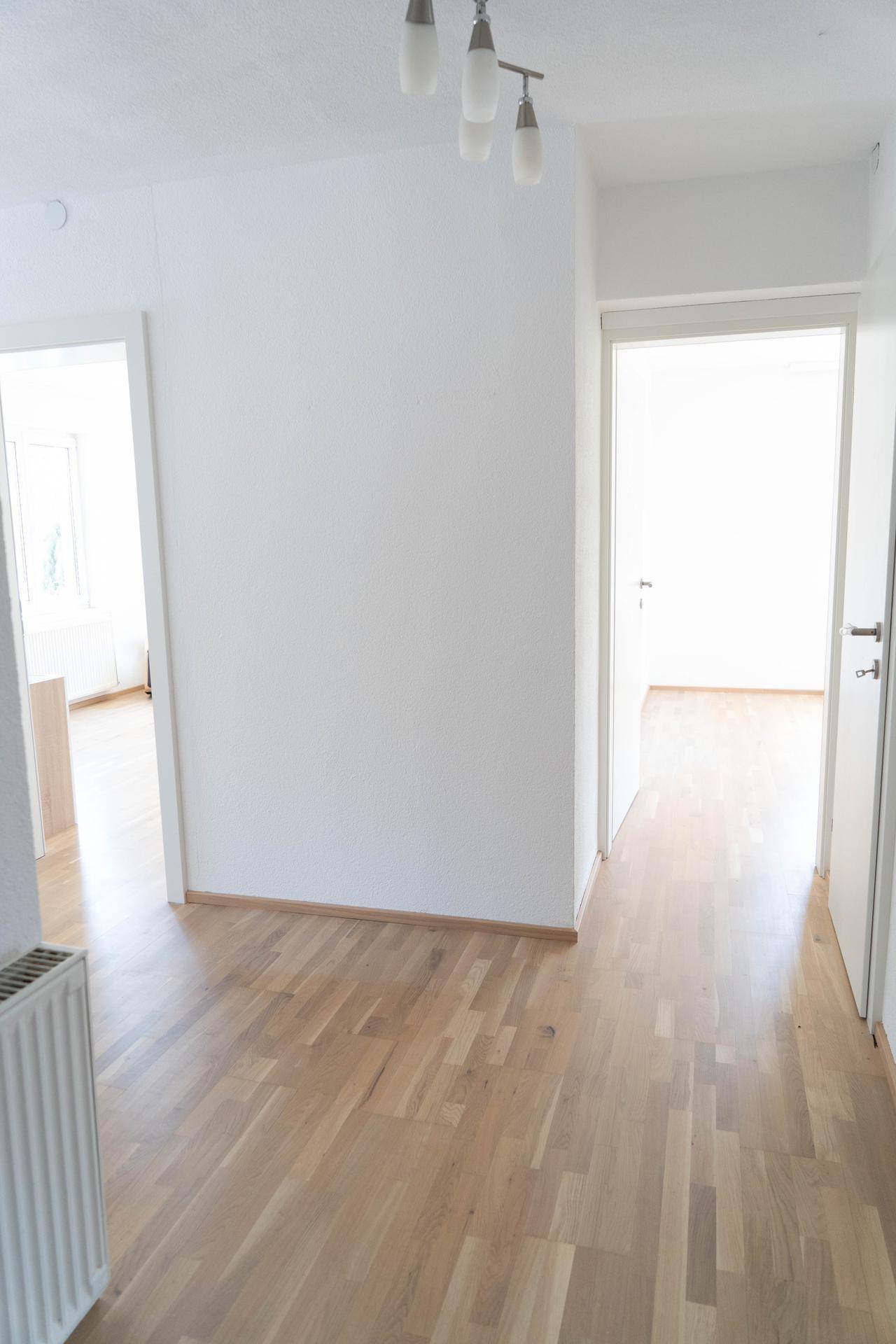 Heller Flur mit Parkettboden, der zu verschiedenen Zimmern der Wohnung führt.