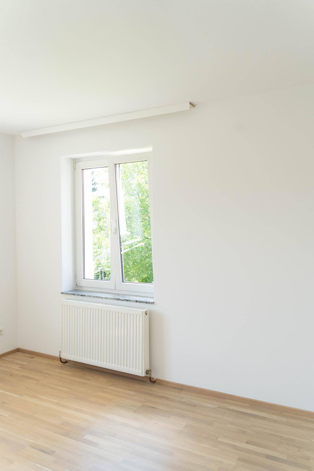 Lichtdurchflutetes Zimmer mit Parkettboden und einem Fenster, das eine angenehme Atmosphäre schafft.