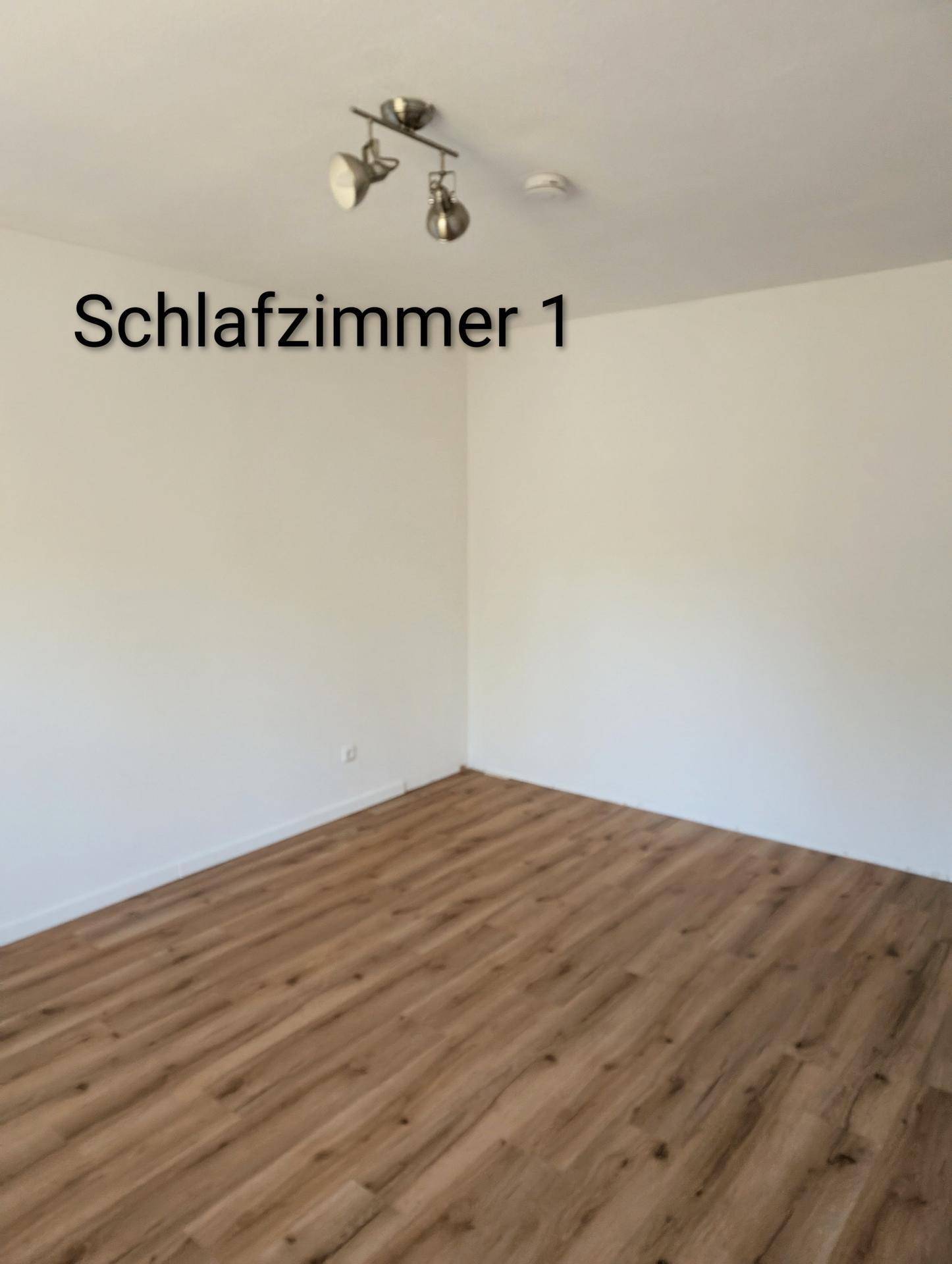 Geräumiges Schlafzimmer mit hellem Laminatboden und weiß gestrichenen Wänden, unmöbliert und sauber.