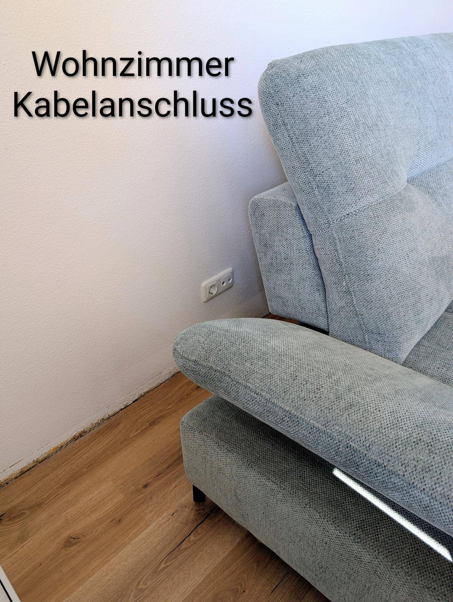 Detailansicht eines modernen Sofas im Wohnzimmer mit Kabelanschluss an der Wand.