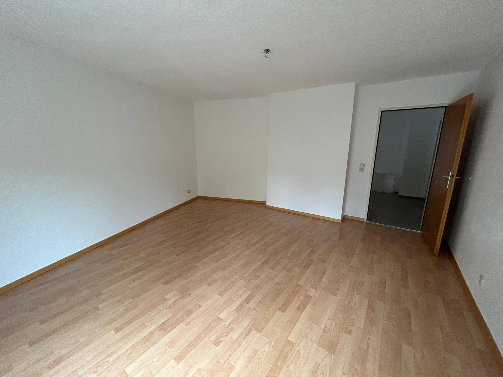 Geräumiges Zimmer mit Laminatboden und weiß gestrichenen Wänden, bereit zur individuellen Gestaltung.