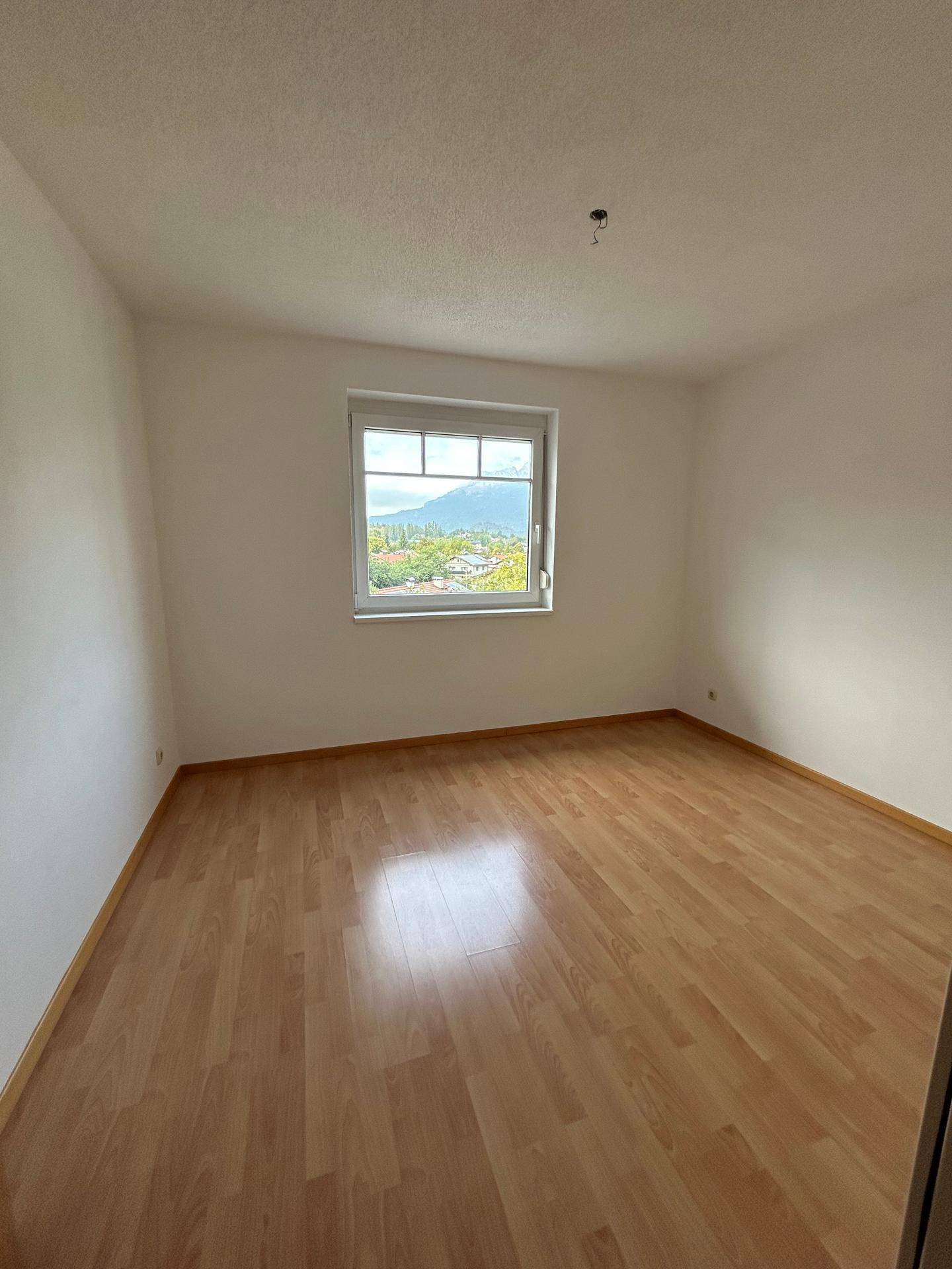Helles Zimmer mit Laminatboden und einem Fenster, das einen weiten Blick bietet.