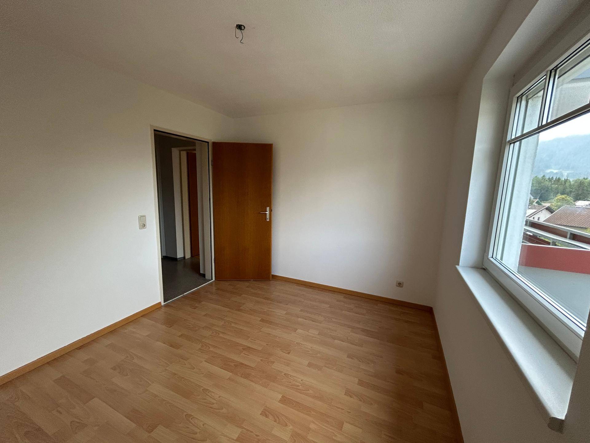 Geräumiges Zimmer mit Laminatboden und einem Fenster, das viel Tageslicht hereinlässt.