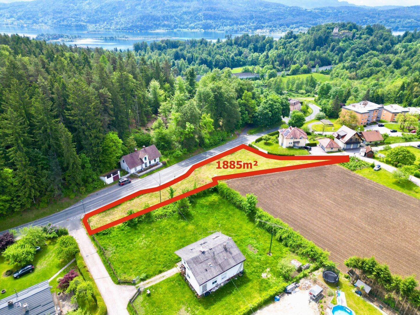Luftaufnahme des Baugrundstücks mit Blick auf den See und die umliegende Berglandschaft.