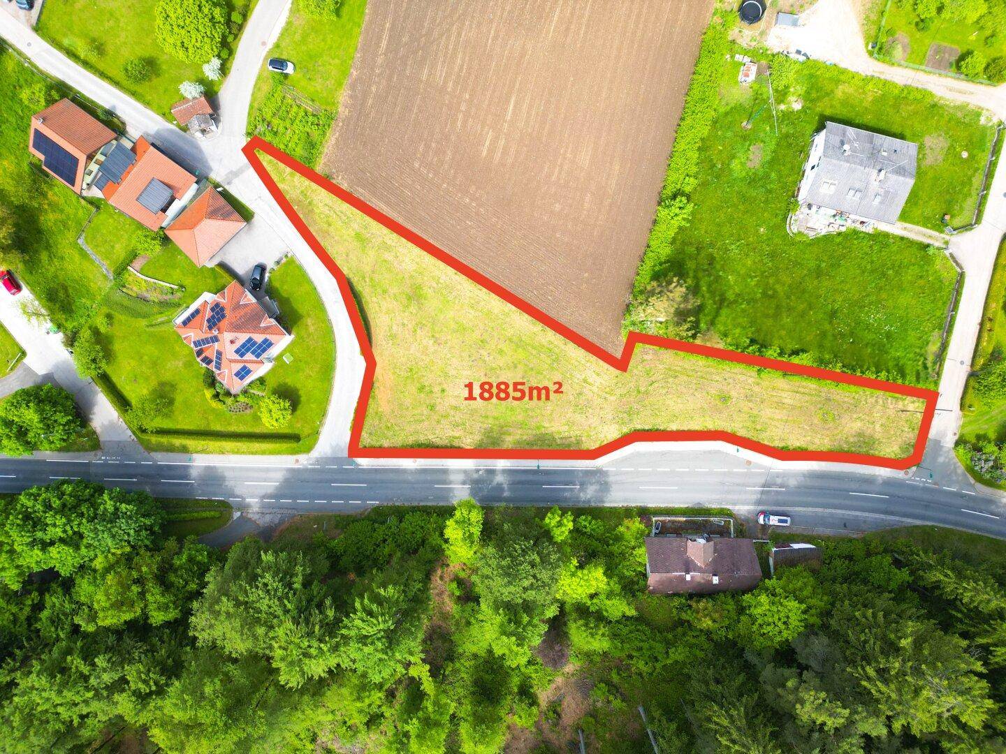 Nahaufnahme des 1885m² großen Baugrundstücks mit angrenzender Straße und umliegenden Häusern.