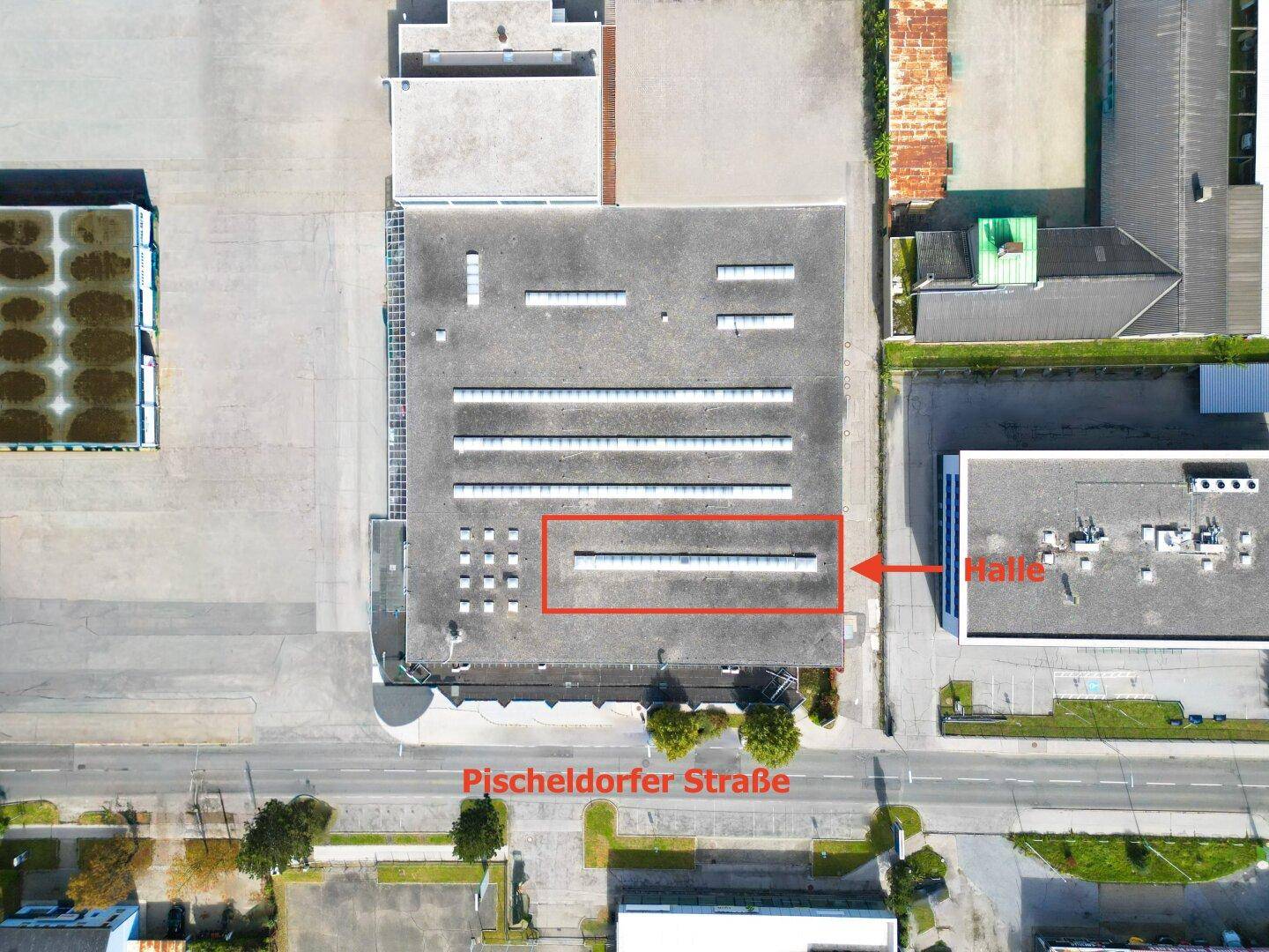 Senkrechte Luftaufnahme eines Gewerbegebäudes mit Flachdach und Oberlichtern, die die Pischeldorfer Straße zeigt.