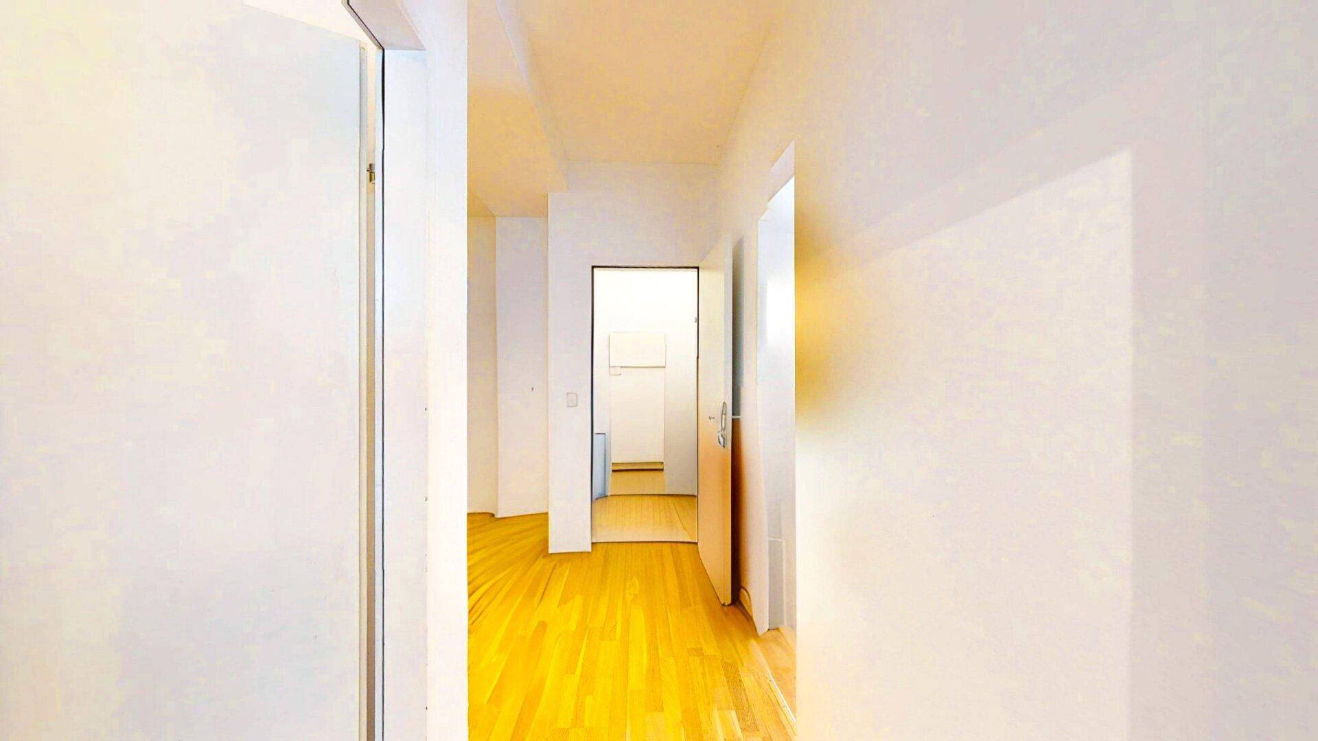 Langer, heller Flur mit Holzparkettboden und weißen Wänden, der weitere Räume erschließt.