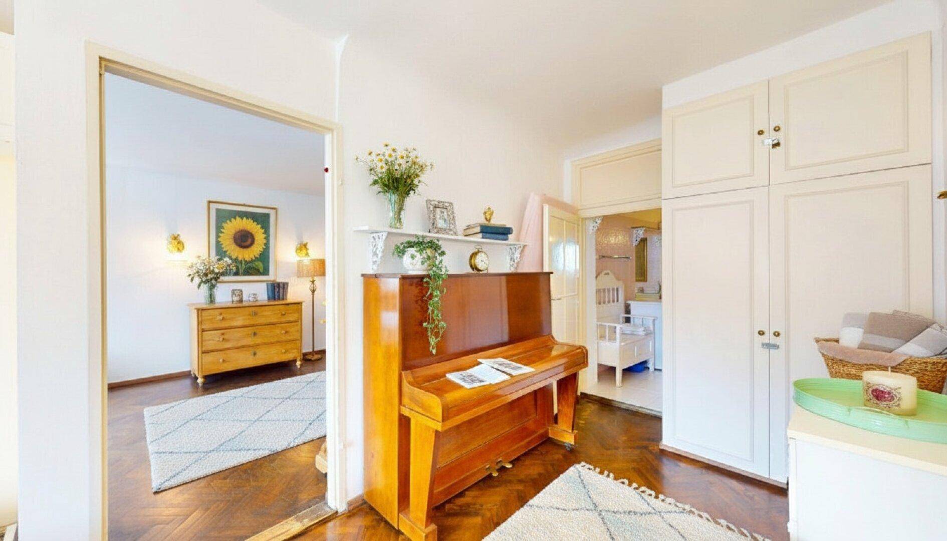 Flur mit Holzklavier, Einbauschränken und Zugang zu weiteren Zimmern.