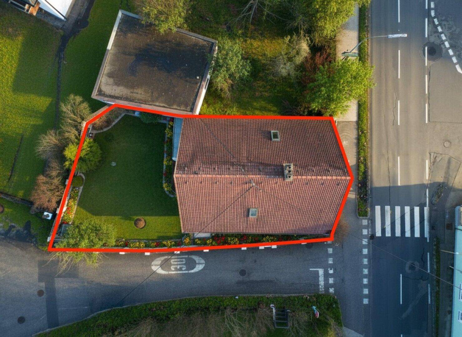 Draufsicht des Hauses mit rotem Ziegeldach und dem umliegenden Gartenbereich von oben.